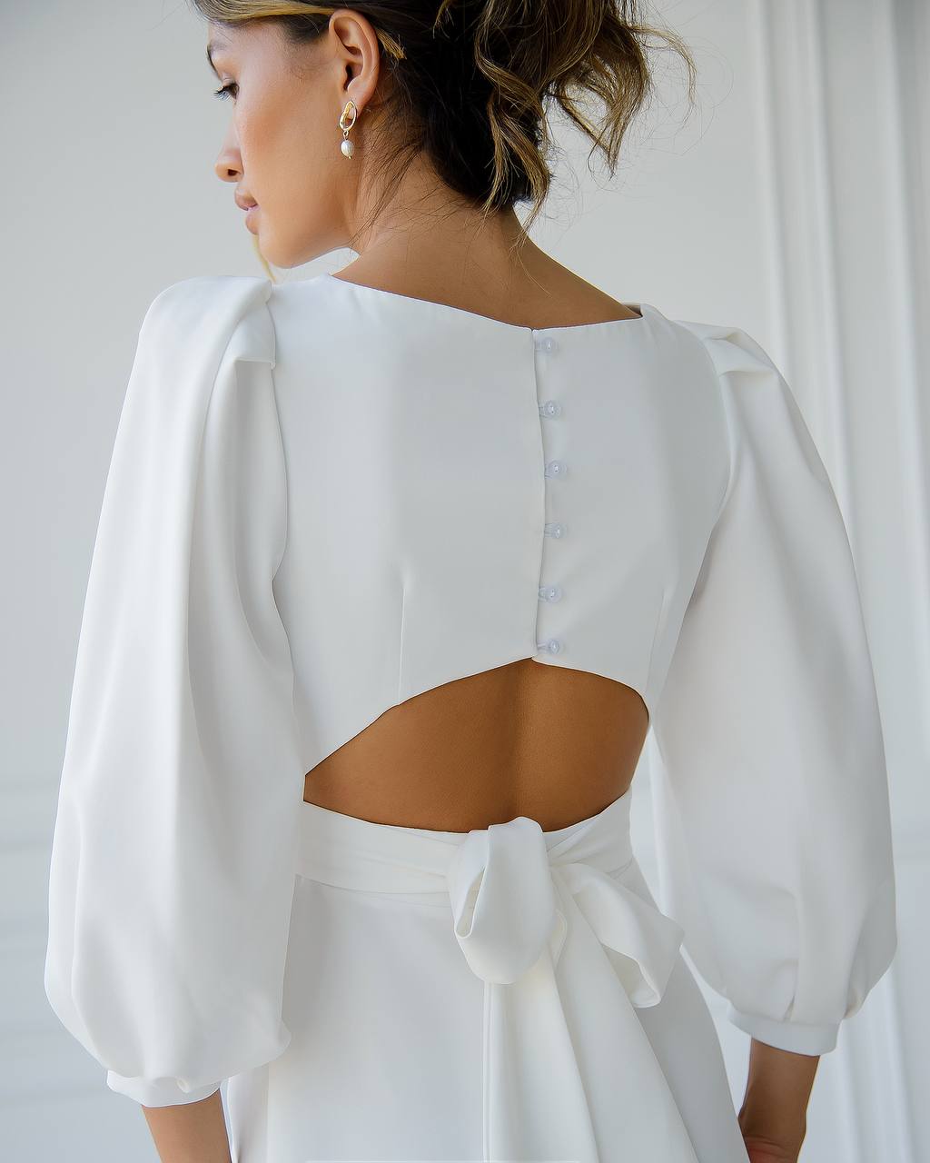 White dress with cut-out back design on a plain background