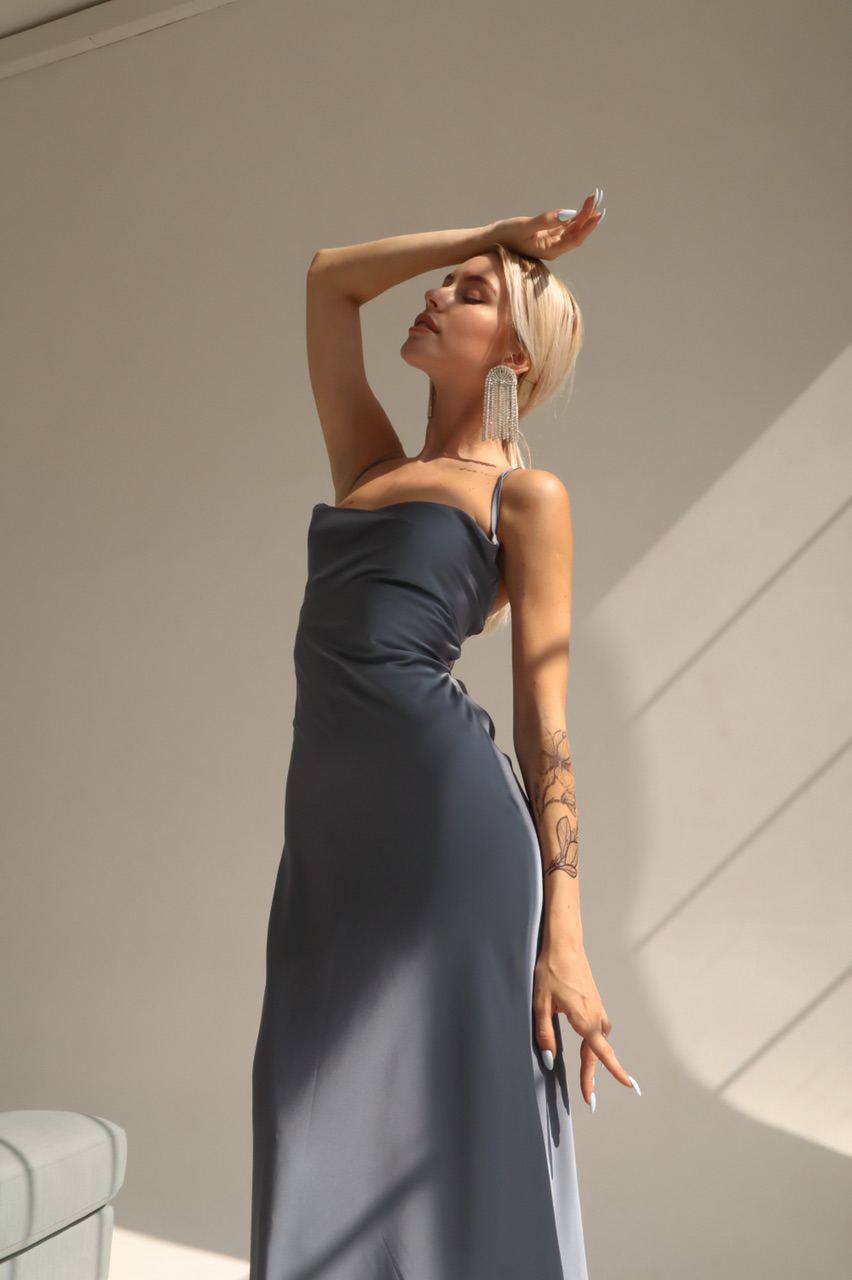 Woman in a gray strapless dress standing against a neutral wall.