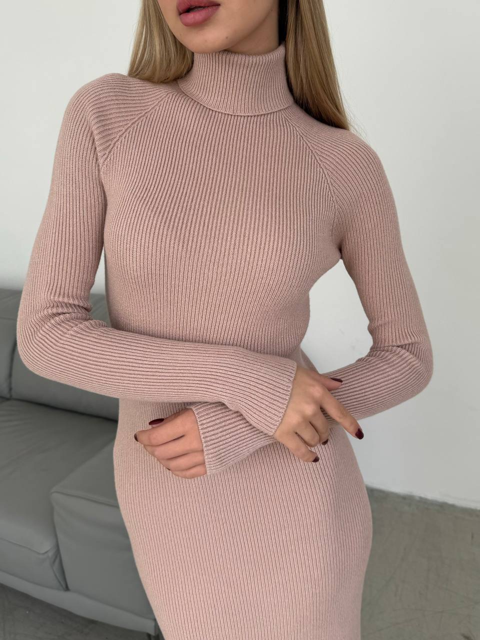 Person wearing a ribbed pink sweater dress against a neutral background