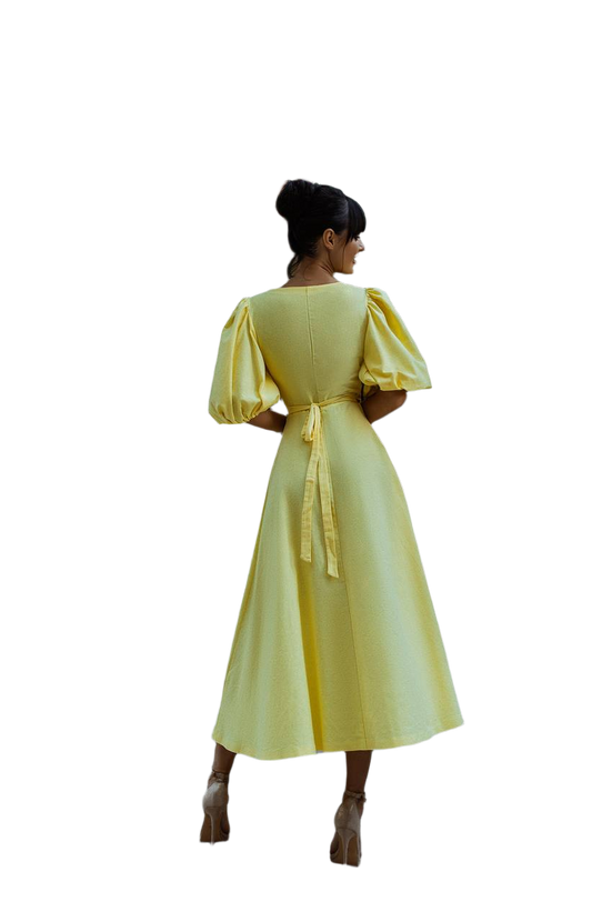 Woman wearing a yellow dress with puffed sleeves on a white background