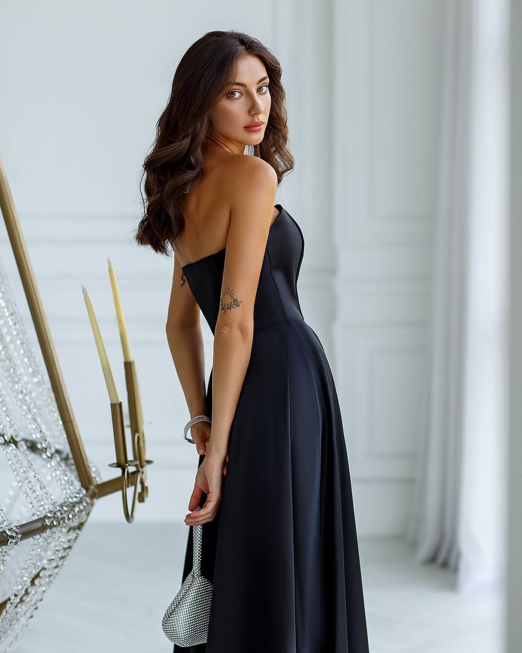 Woman in a black dress standing in a room with decorative elements.