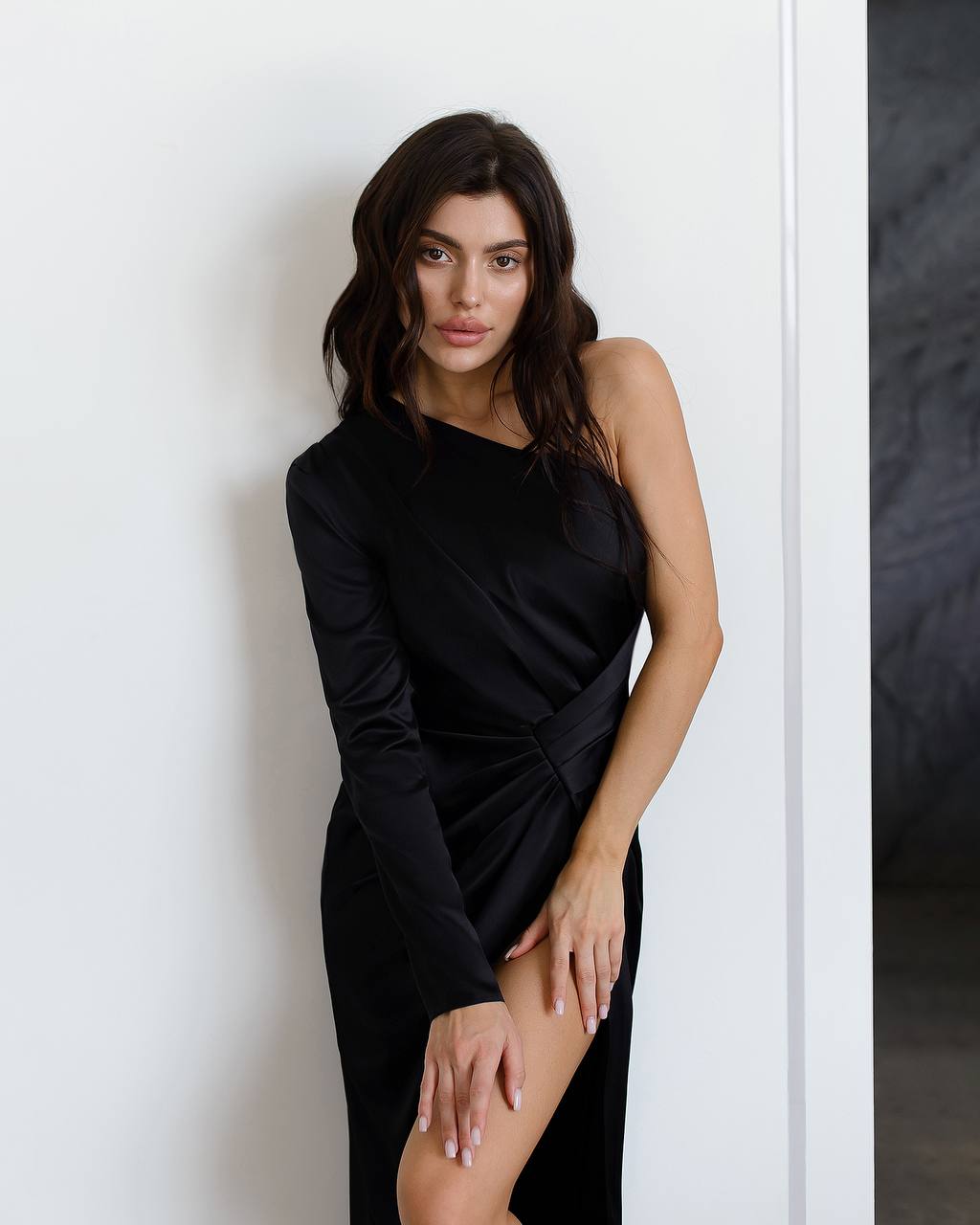 Woman wearing a black dress against a white wall