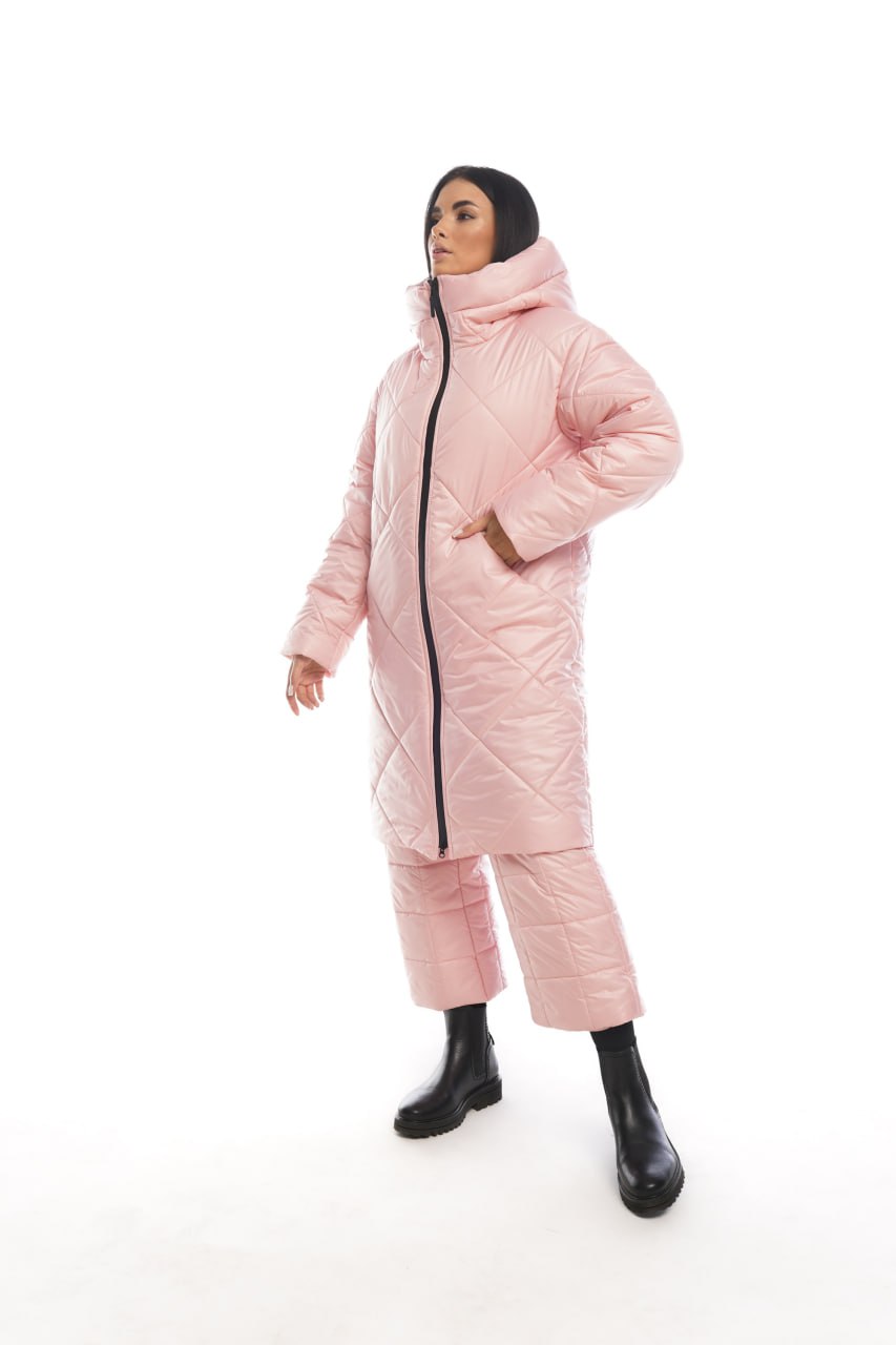 Person wearing a pink quilted coat and pants on a white background