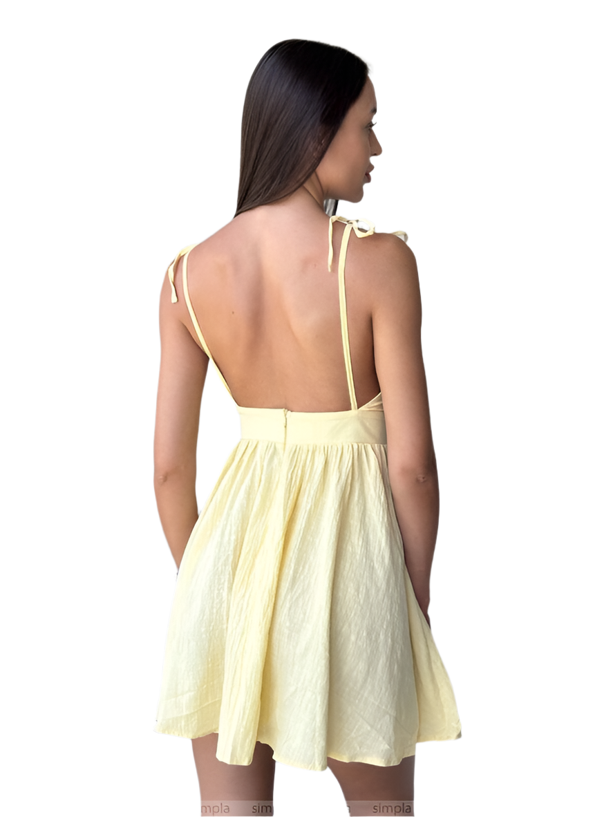 Woman wearing a light yellow dress with thin straps on a white background