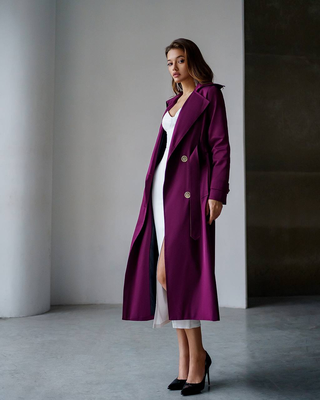 Woman wearing a long purple coat in a minimalistic setting