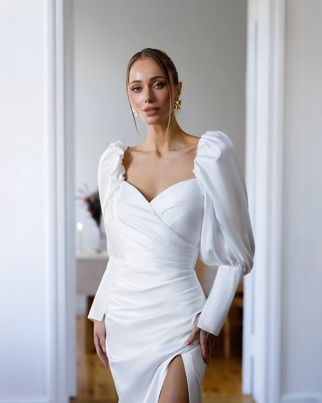 Woman wearing a white dress with puffed sleeves in an indoor setting