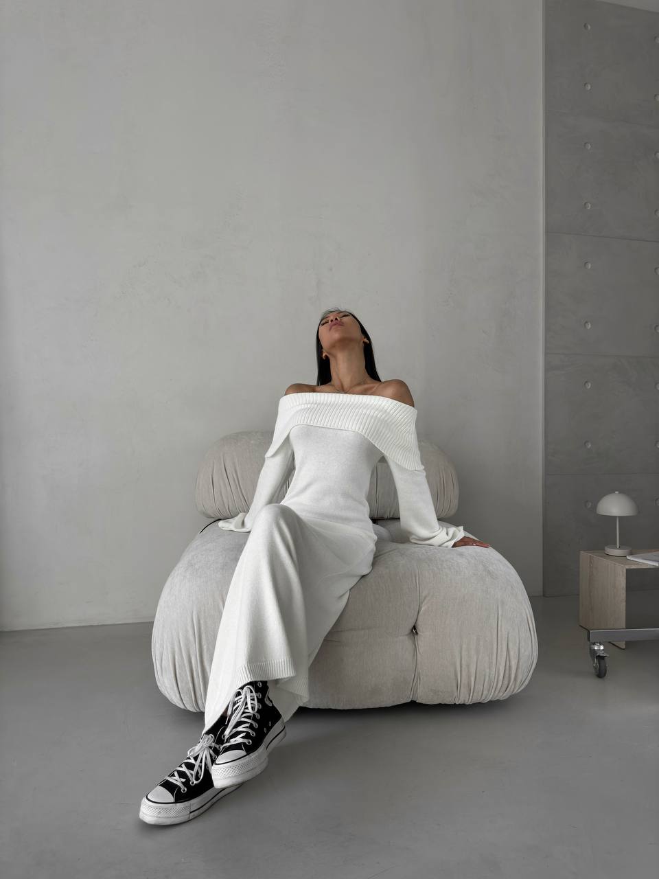Person sitting on a gray bean bag chair in a minimalistic room.