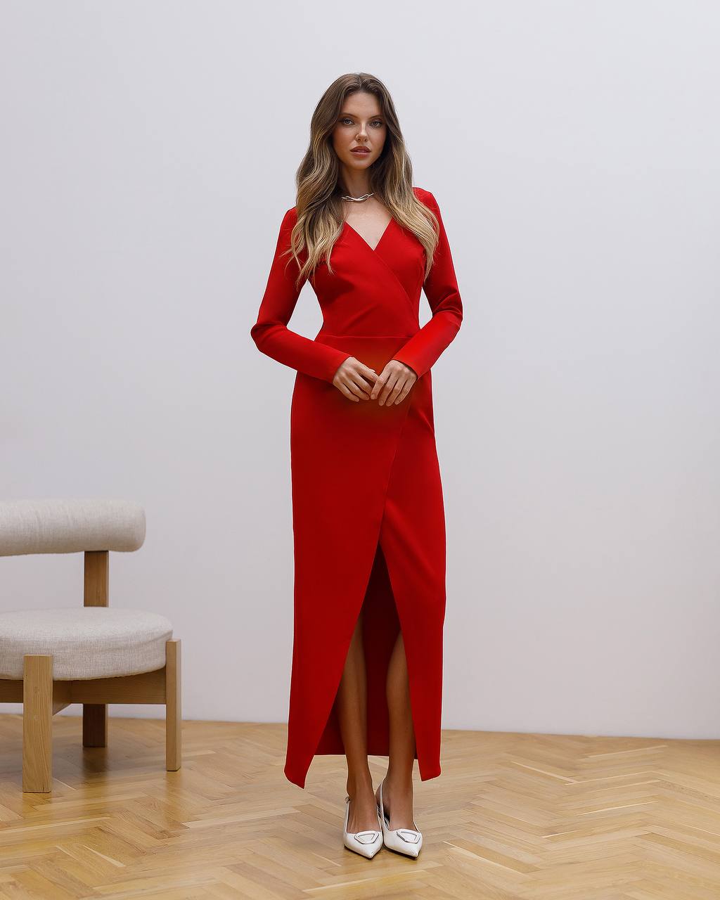 Woman wearing a red dress with a slit on a wooden floor.
