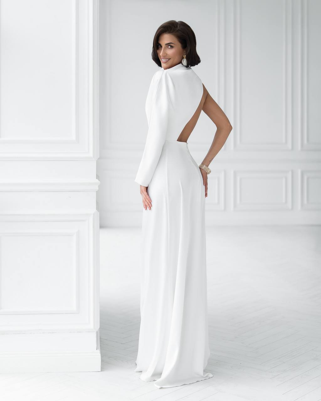 Woman wearing a white evening gown with a high slit in a minimalistic setting