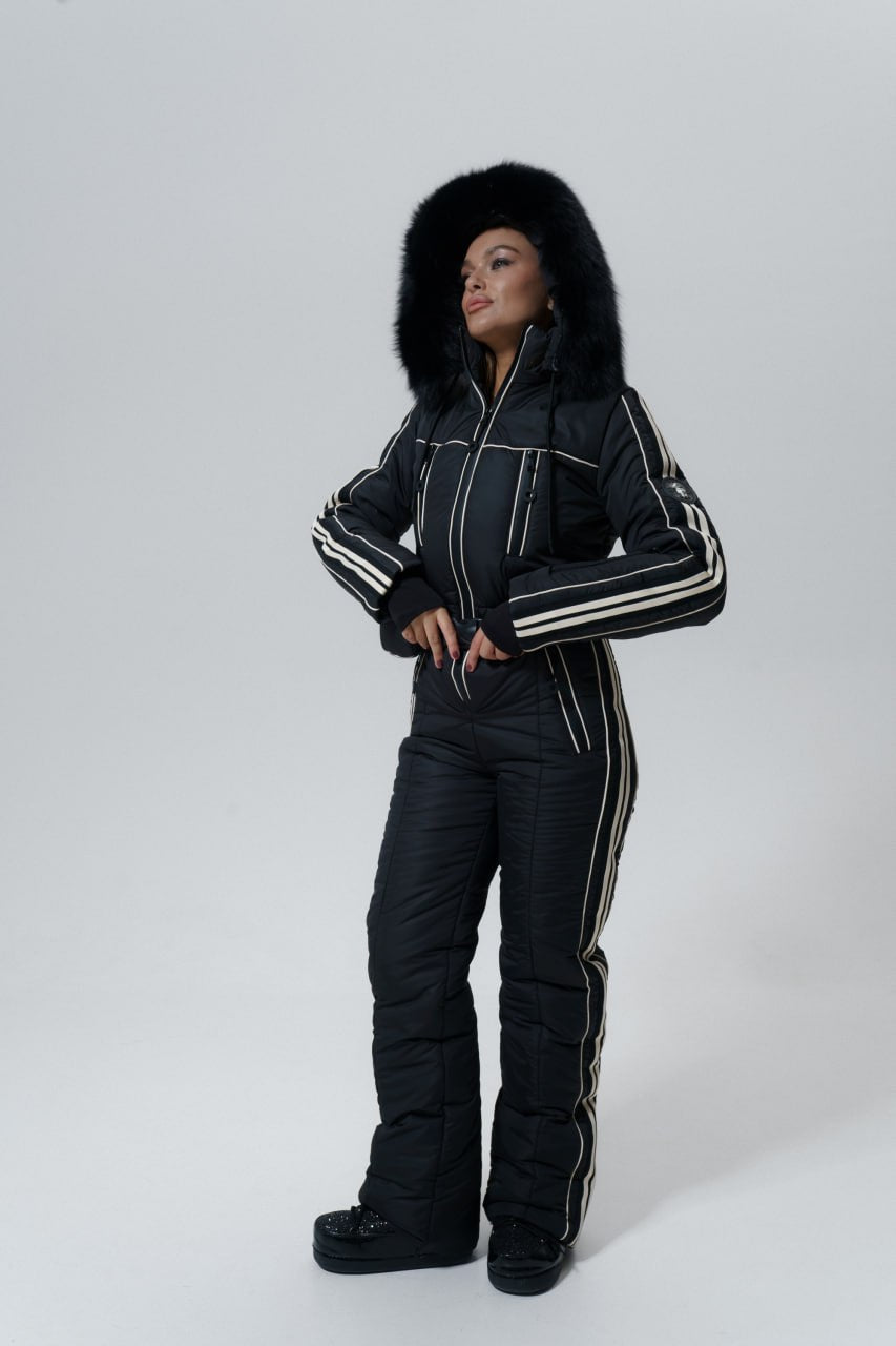 Person wearing a black snowsuit with fur hood on a white background
