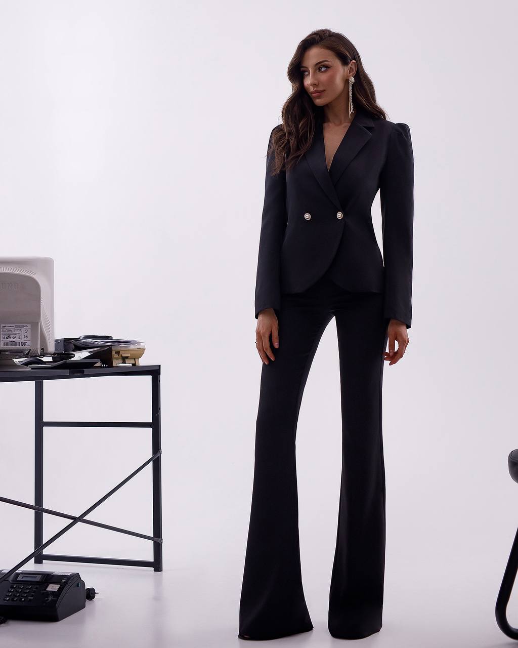 Woman wearing a black suit standing in front of a white background