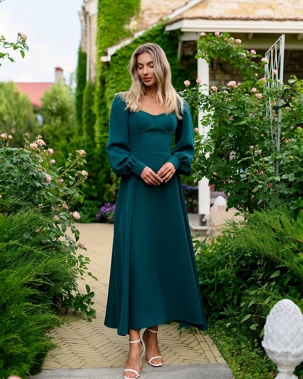 Woman in a teal dress standing in a garden setting