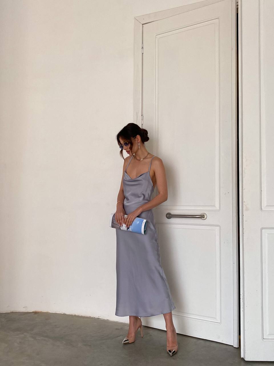 Woman in a gray dress standing in a room with a white door.