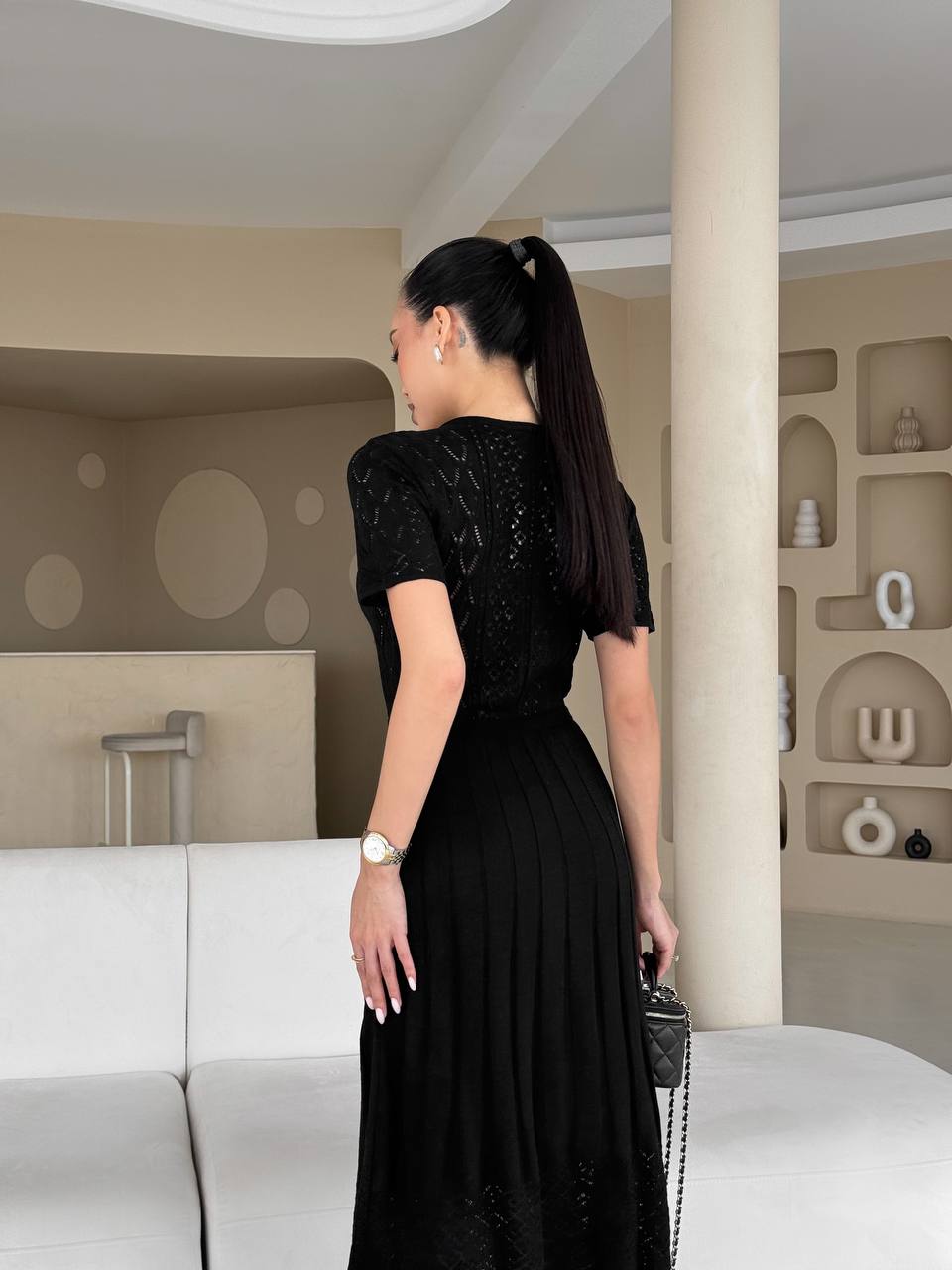Woman in a black dress standing in a modern interior setting