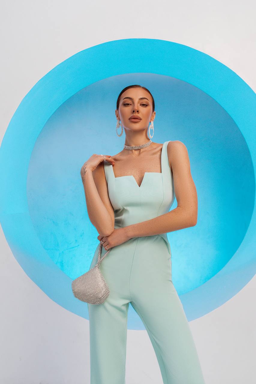 Woman in a light green outfit standing against a blue circular background