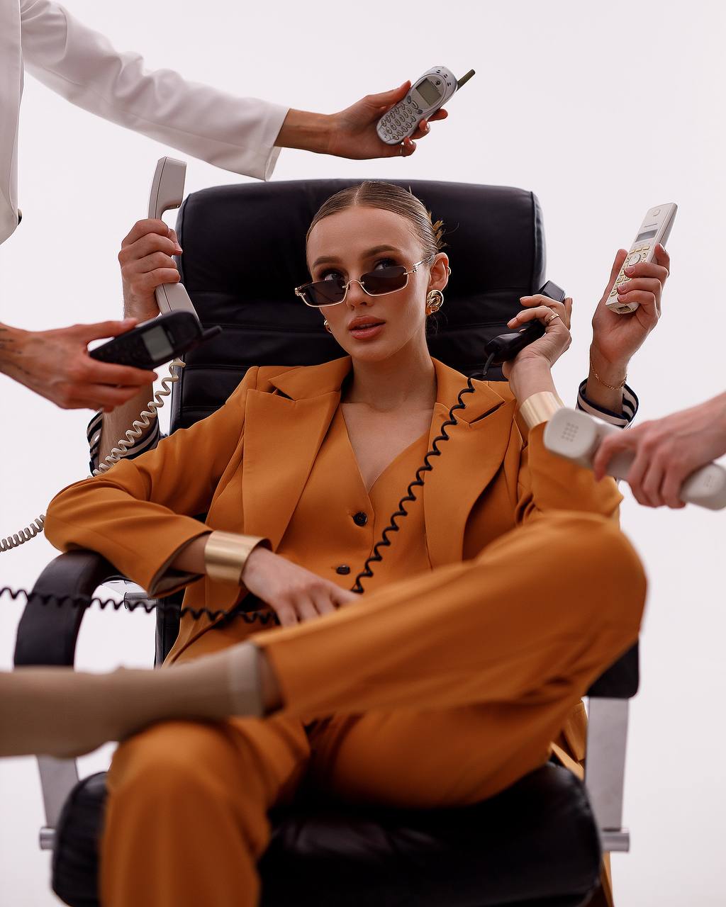 Person in an orange suit sitting in a wheelchair surrounded by multiple phones.