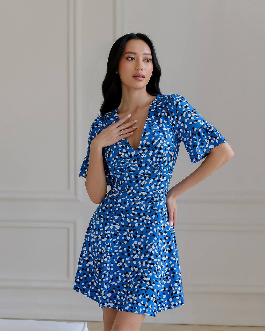 Woman wearing a blue floral dress against a neutral background