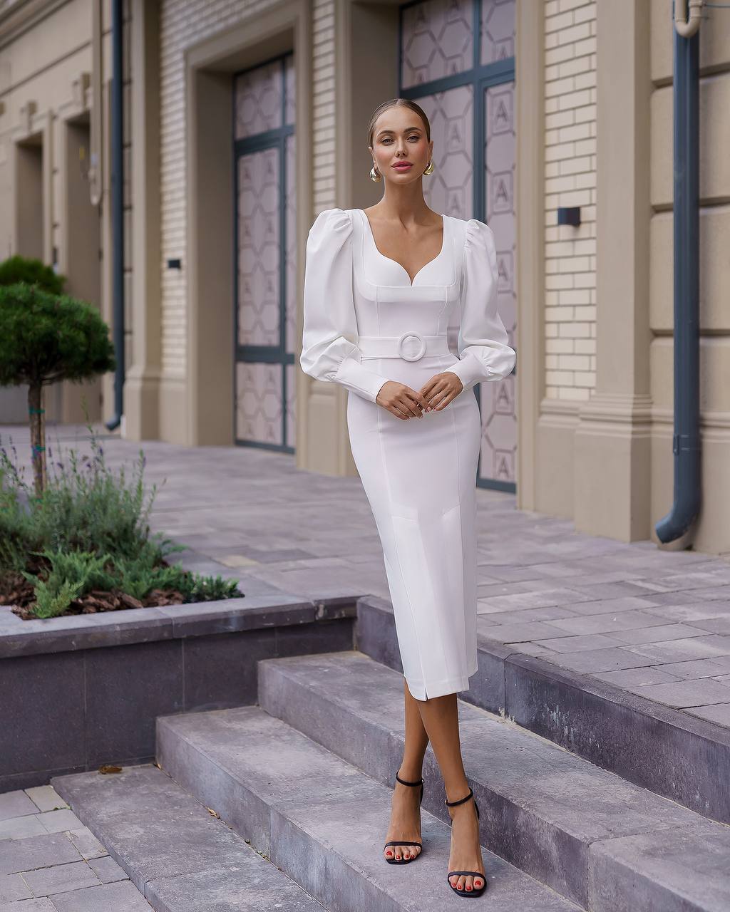 Woman in a white dress standing on steps outside a building