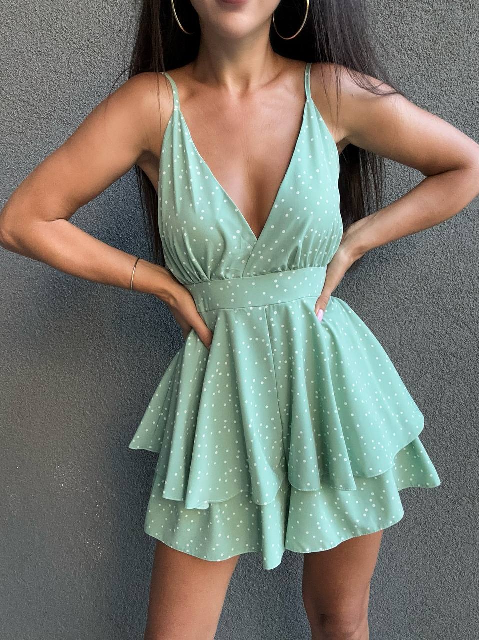 Woman wearing a green polka dot dress against a gray background