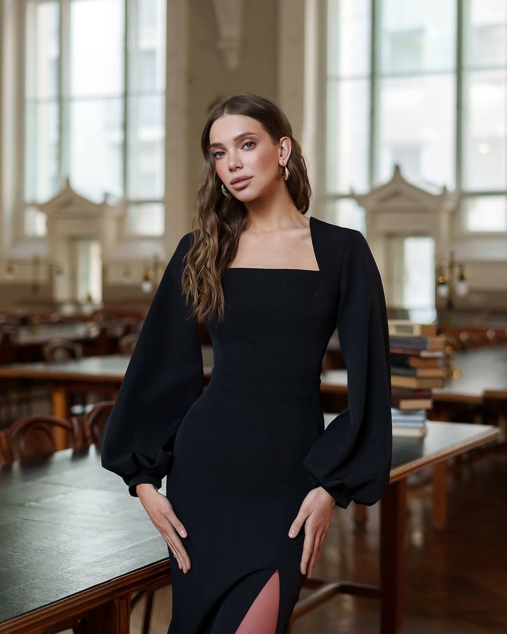 Woman in a black dress standing in a large room with tables and chairs.