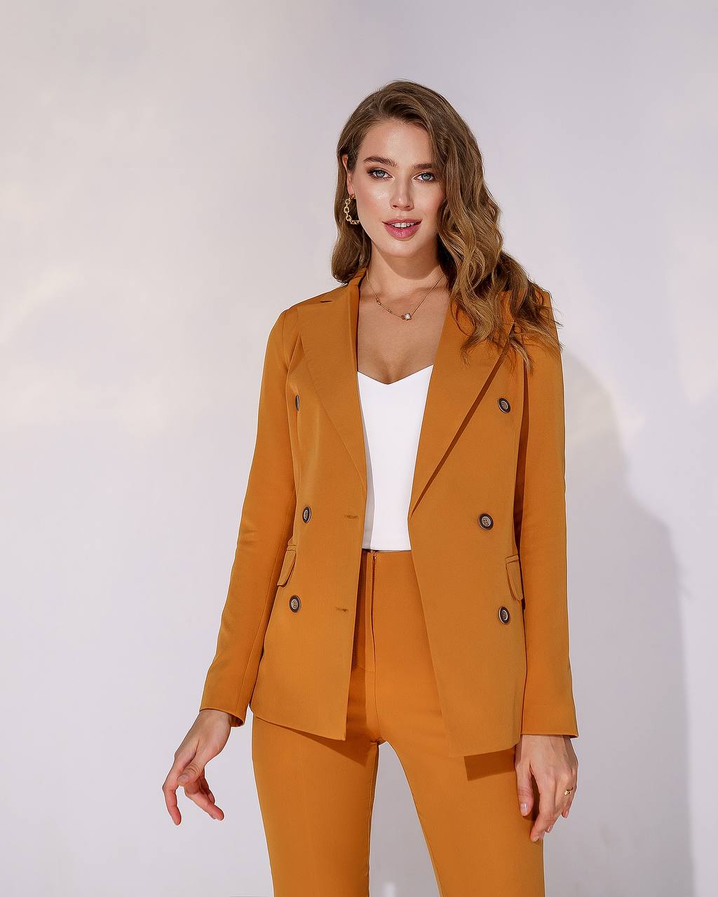 Woman wearing a mustard yellow suit against a white background