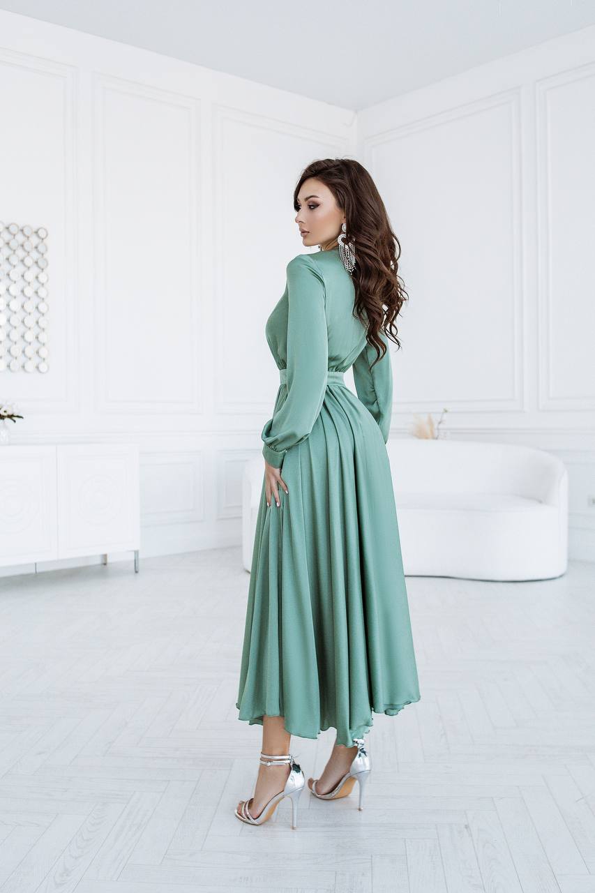 Woman in a green dress standing in a white room