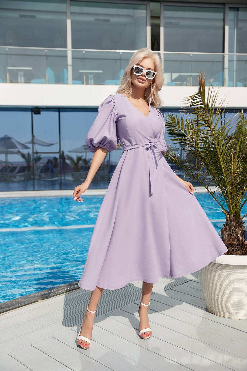 Woman in a lavender dress standing by a poolside