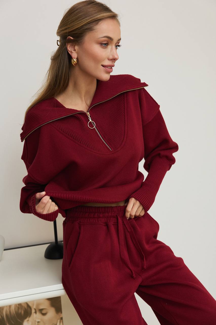Woman wearing a burgundy outfit sitting on a white surface.