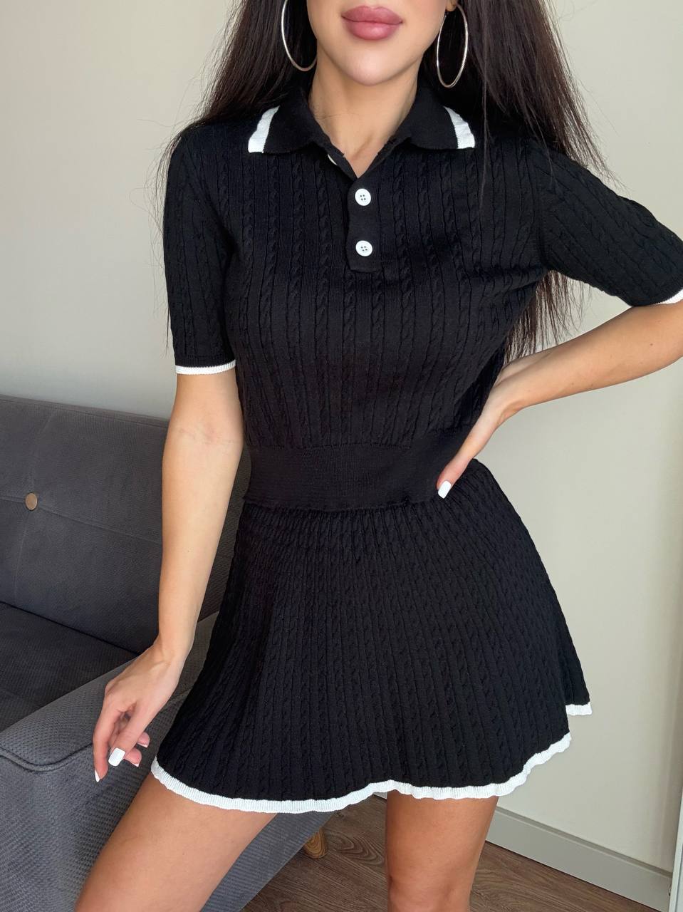 Woman wearing a black knit dress with white trim in an indoor setting.