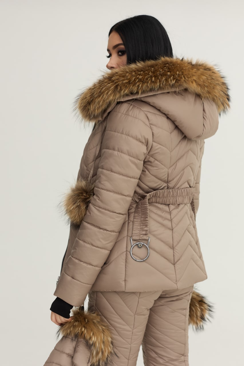 Person wearing a beige puffer coat with fur trim on a plain background