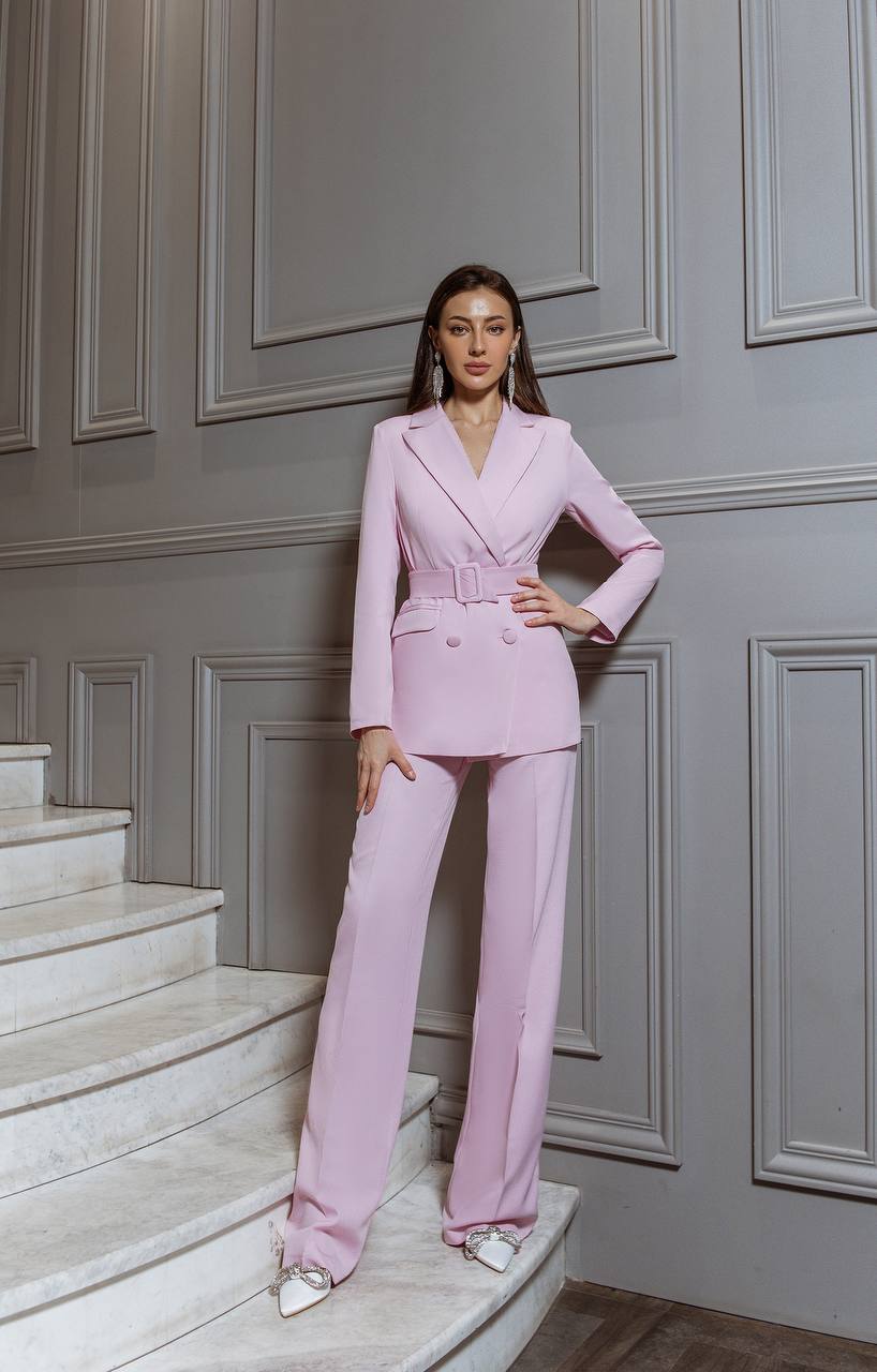 Woman in a pink suit standing on a staircase with a gray paneled wall background
