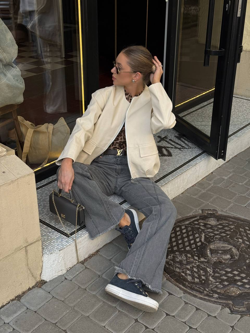 Woman in a stylish outfit sitting on a step outside a building.