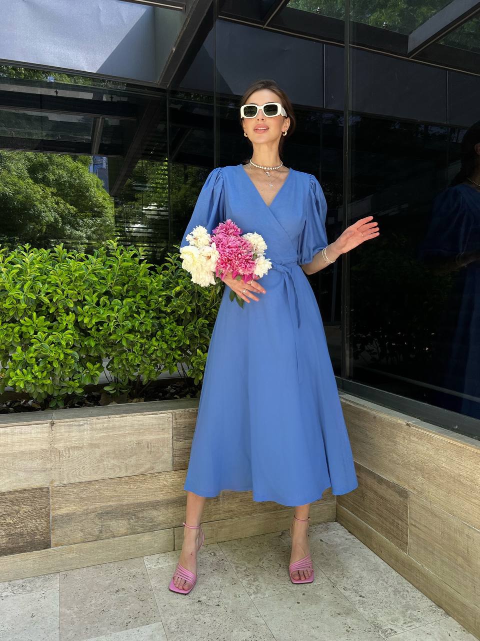 Woman in a blue dress holding flowers outdoors