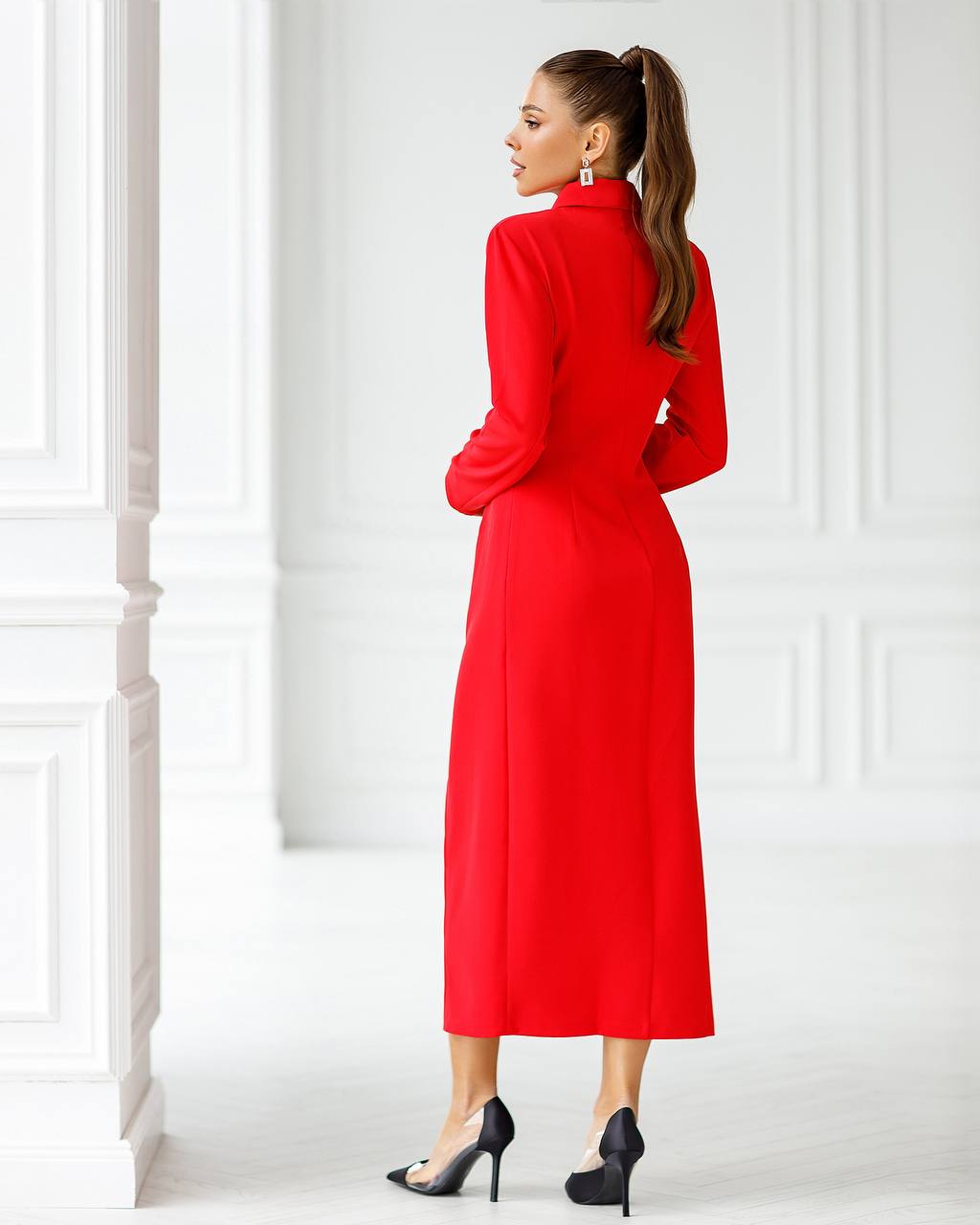 Woman wearing a red dress standing in a white room