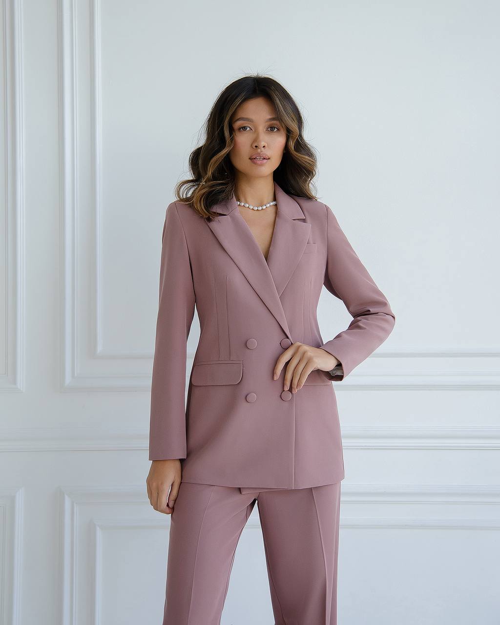 Woman wearing a pink suit against a white wall