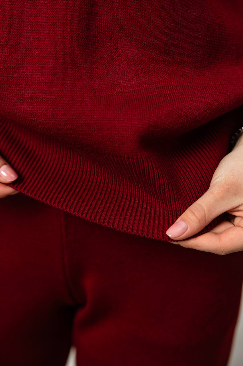 Close-up of a person wearing a burgundy sweater with hands adjusting the fabric.