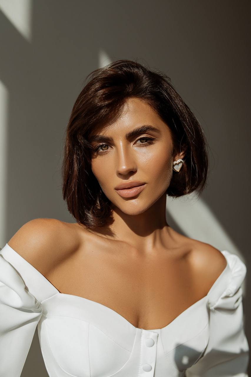 Woman wearing a white off-shoulder top with a neutral background