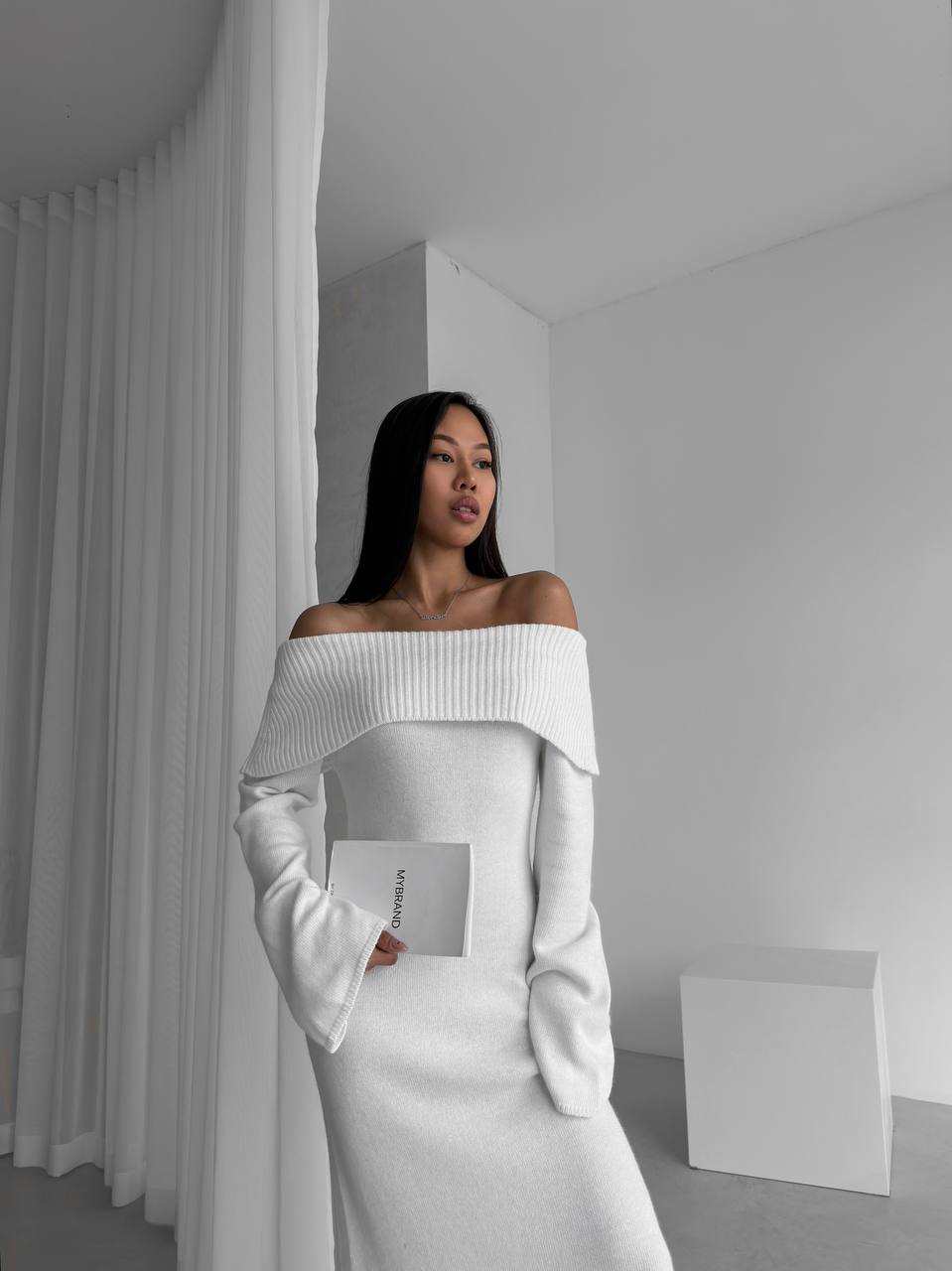 Woman wearing a white off-shoulder outfit in a minimalistic setting