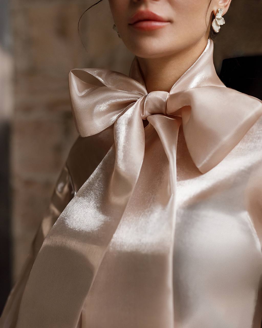 Close-up of a person wearing a large satin bow tie with a blurred background
