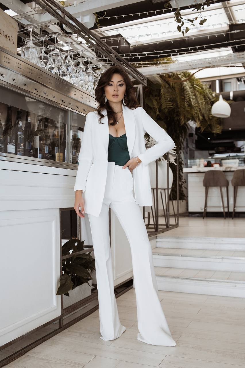 Woman in a white suit standing in a modern interior setting