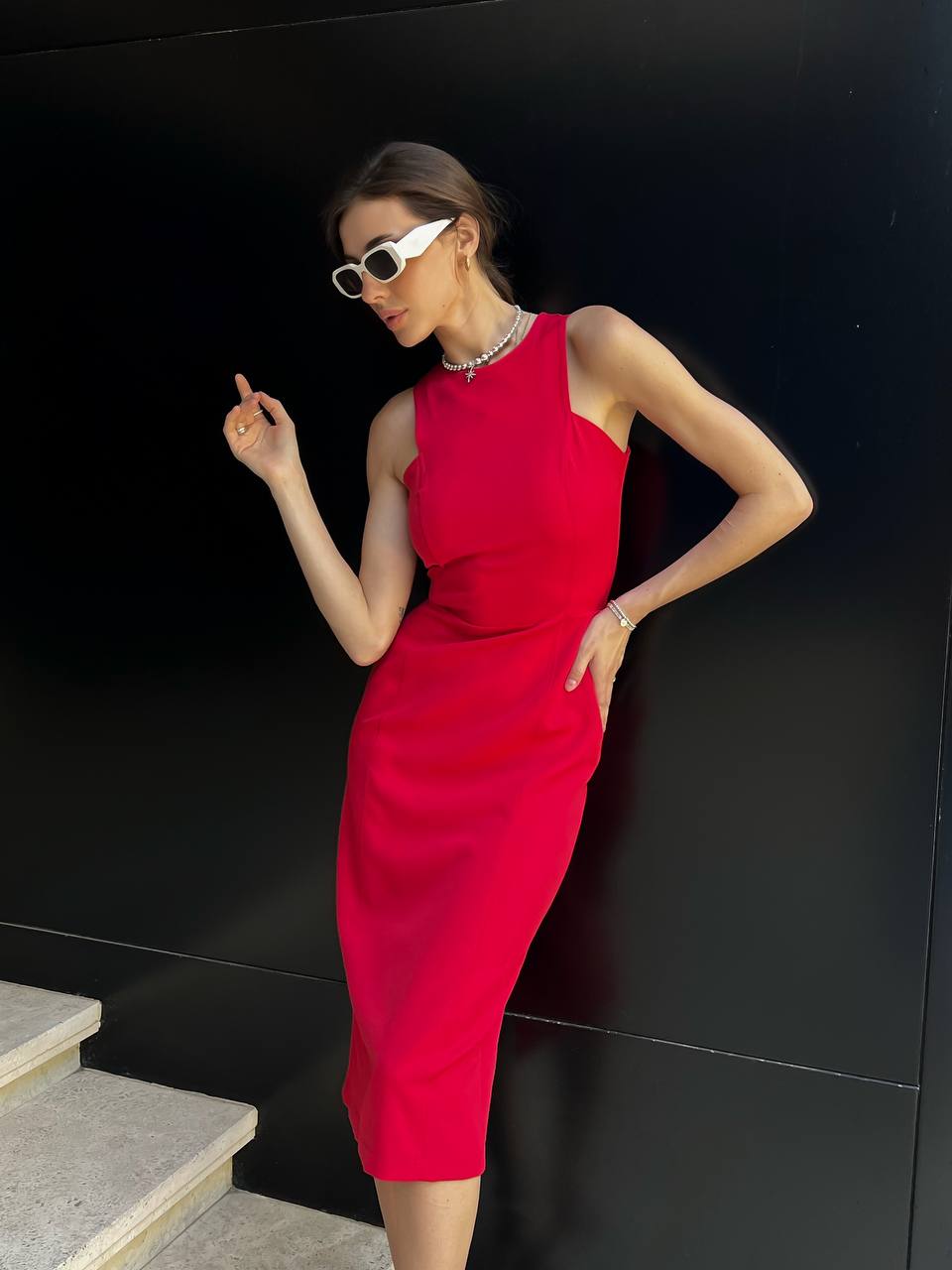 Woman in a red dress posing against a black wall