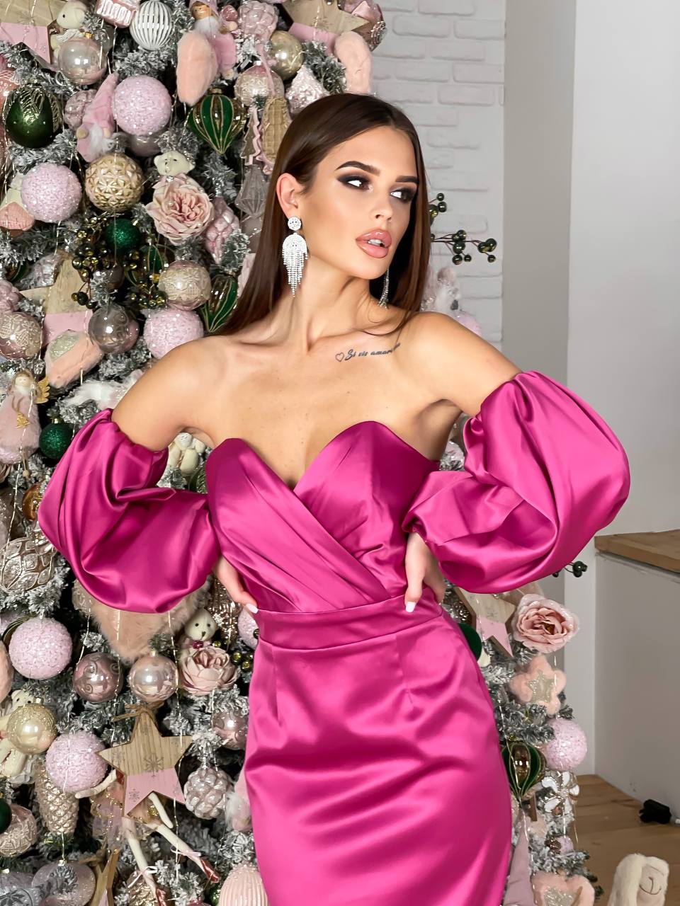 Woman in a pink dress standing in front of a decorated Christmas tree.