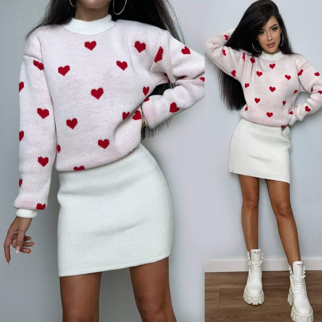 Woman wearing a pink sweater with red heart patterns and a white skirt.
