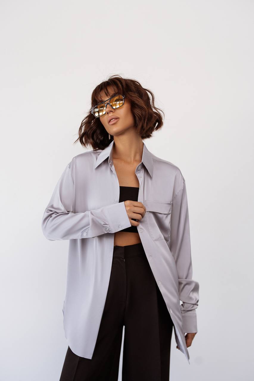 Woman wearing a light gray oversized shirt and black pants on a white background