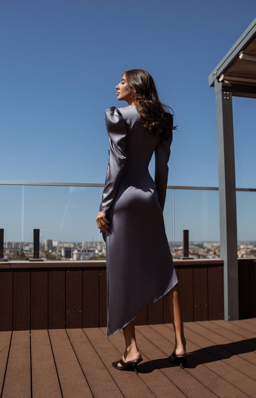 Woman in a gray dress standing on a rooftop with a cityscape in the background