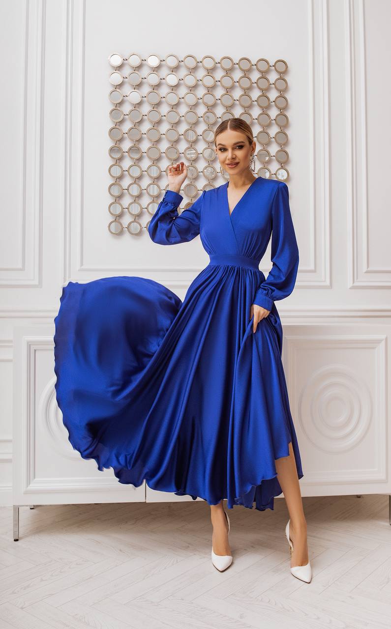 Woman wearing a blue dress in an elegant room with decorative wall.