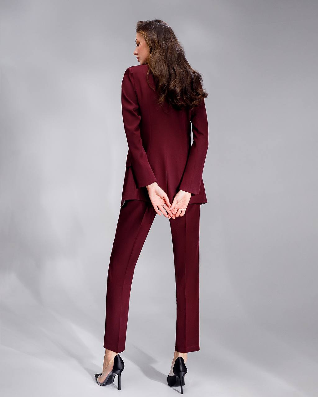 Woman wearing a burgundy suit on a gray background