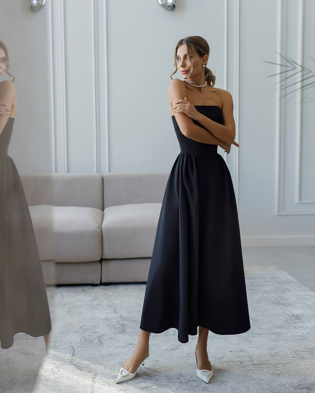 Woman wearing a black strapless dress in a modern interior setting