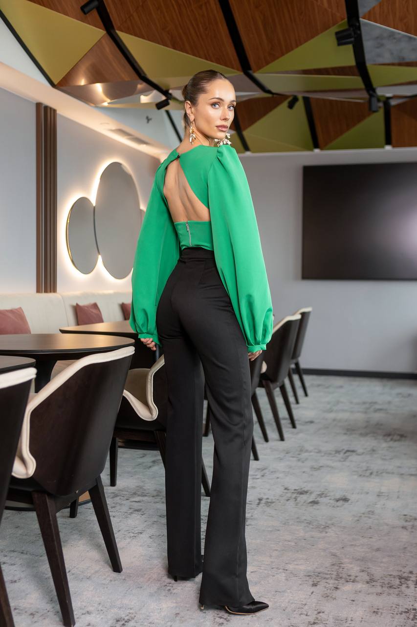 Woman in a green top and black pants standing in a modern restaurant setting