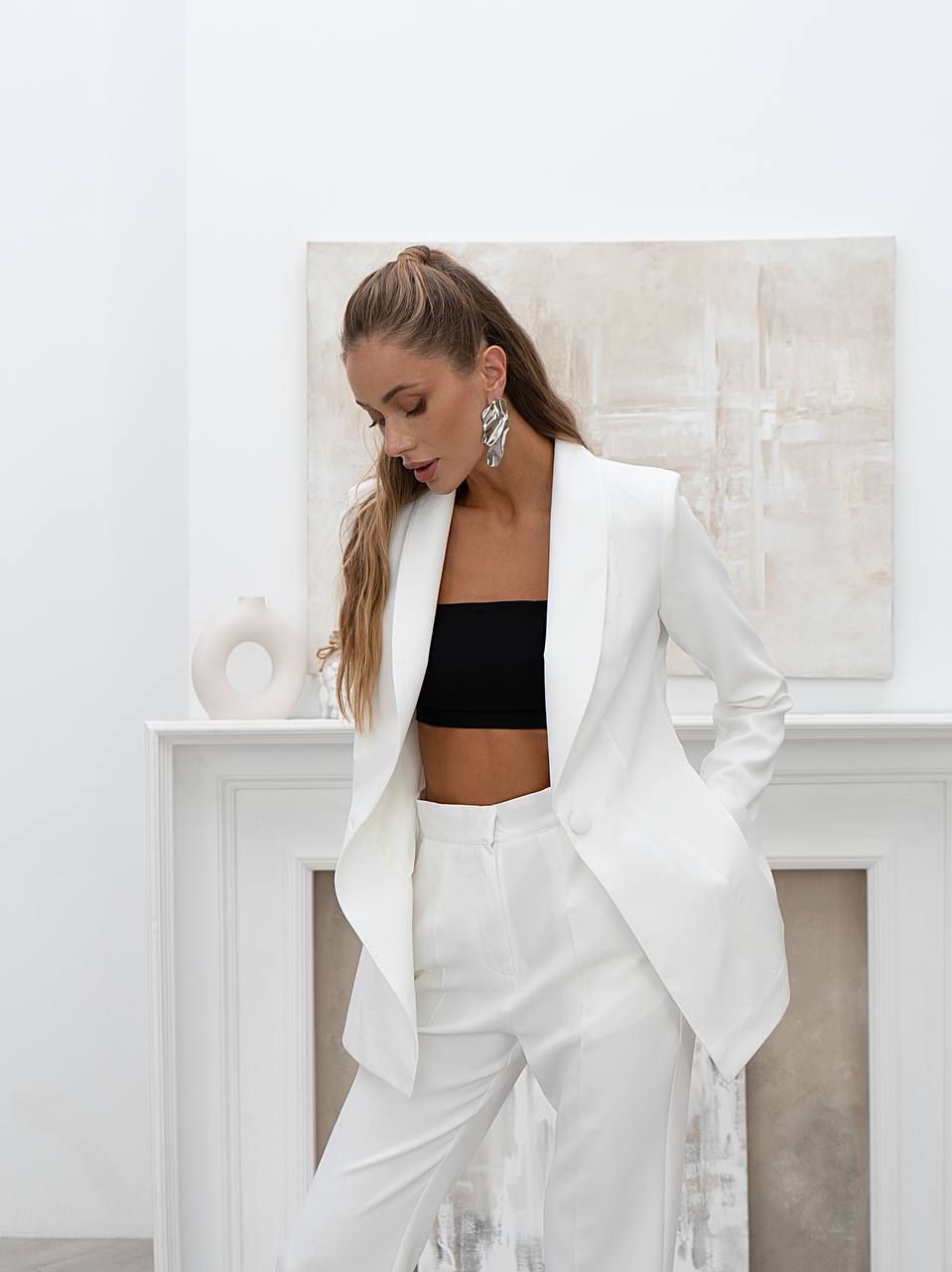 Woman wearing a white suit with a black top in an elegant room.
